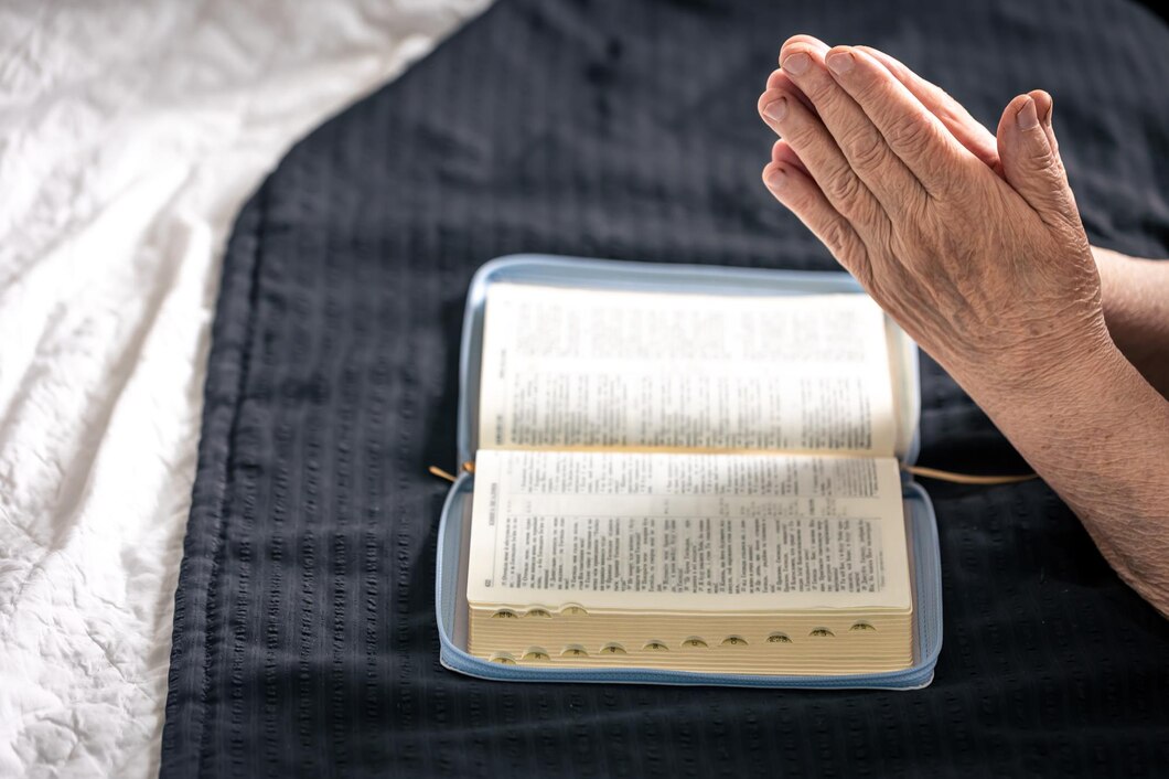 hands-elderly-woman-folded-prayer-front-book-bible_169016-36158