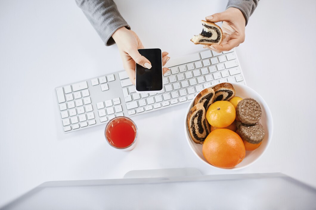 high-angle-shot-woman-having-lunch-front-computer-holding-rolled-cake-smartphone-busy-woman-eat-while-working-waste-time-finish-project-time-enjoying-drinking-fresh-juice_176420-8718